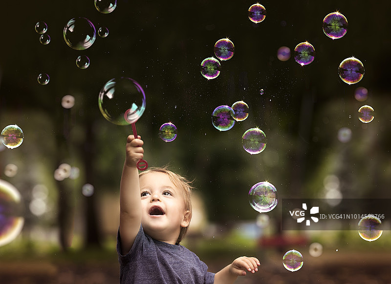 2岁的兄弟双胞胎男孩抱着一个泡泡，在公园里玩浮动的泡泡图片素材