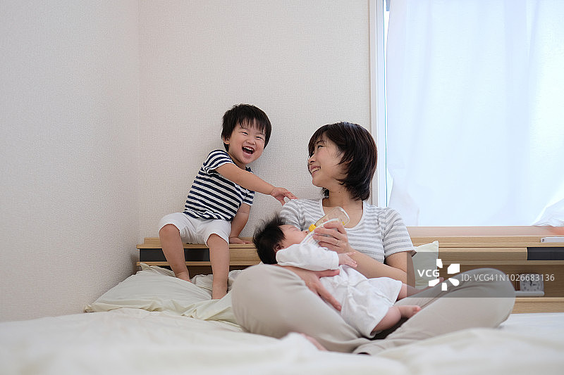母亲，婴儿和幼儿坐在床上图片素材