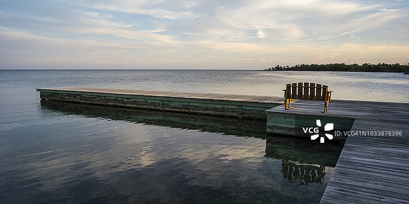 码头上的一条木凳，日出时面向海岸线和开阔的海洋图片素材
