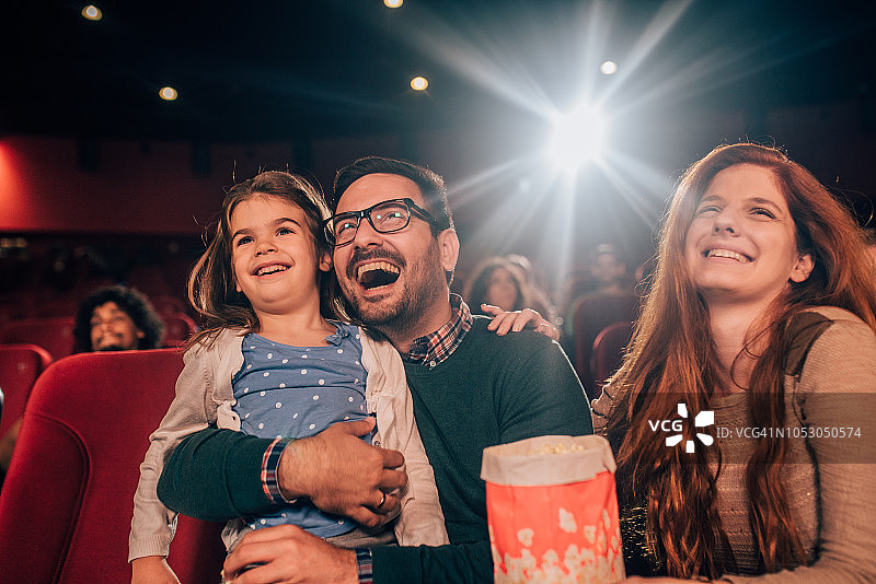 欢笑的年轻家庭在电影院图片素材