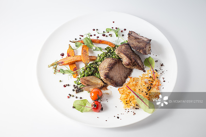 烤肉配芝士，胡萝卜，洋葱，青菜和西红柿放在白色的盘子里图片素材