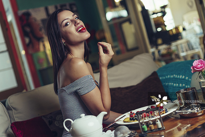 年轻女士在舒服的咖啡店吃甜水果和华夫饼图片素材