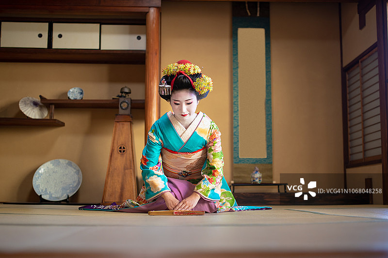 舞子女孩坐在脚跟和鞠躬在传统的日本榻榻米房间图片素材
