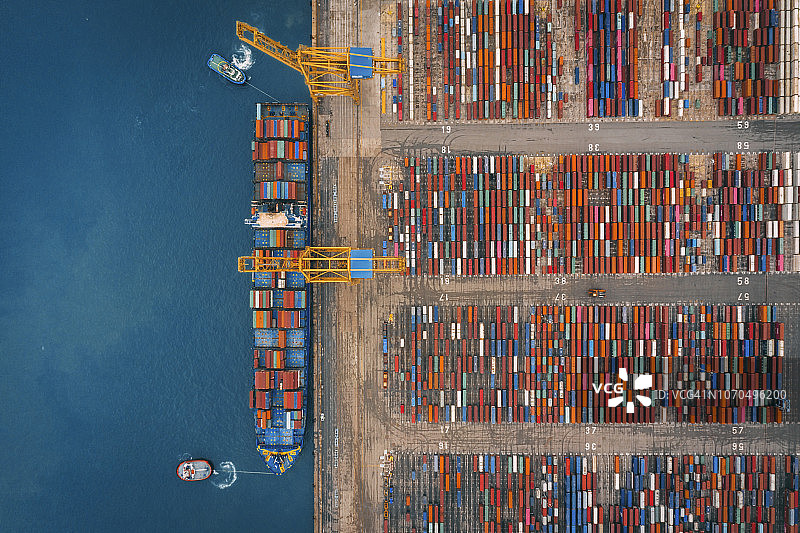 商业港口用岸吊在货轮上装载集装箱的鸟瞰图。图片素材