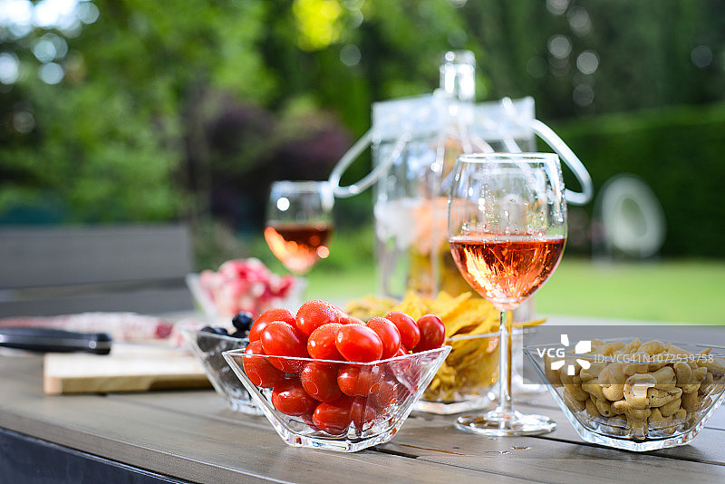 假日夏季早午餐派对桌子户外在房子后院的开胃菜，一杯玫瑰葡萄酒，新鲜饮料和有机蔬菜。图片素材
