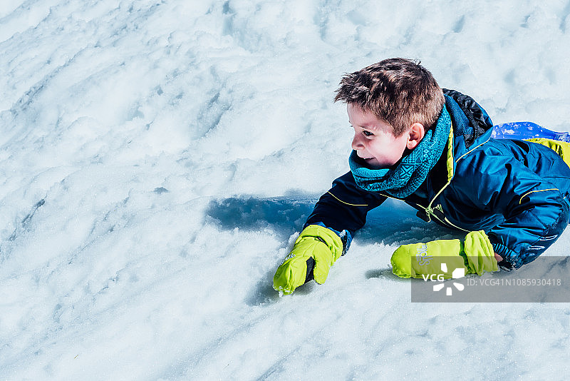 小男孩穿着滑雪服在外面玩雪图片素材