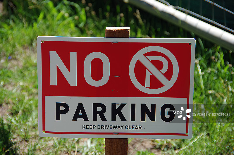 “禁止停车:保持车道畅通”(No parking: Keep driveway clear)的标志插在郊区街道的草地上图片素材