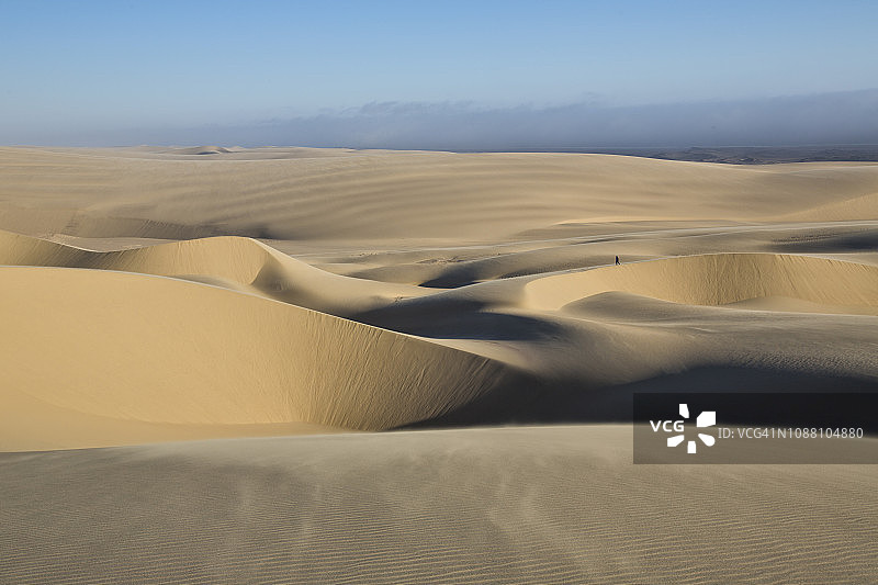 在纳米比亚骨骼海岸国家公园的纳米比亚沙漠中，游客看着美丽的图案无尽的沙丘的4K视图图片素材