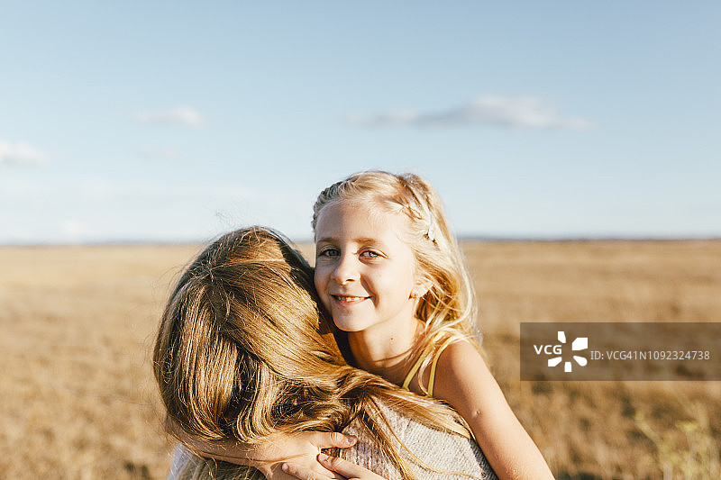 微笑的女儿拥抱母亲的肖像在一个领域图片素材