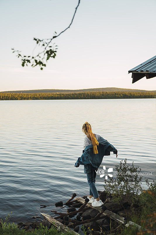 一个年轻女子在湖边，在木板上保持平衡图片素材
