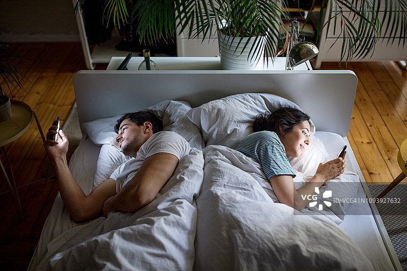 夫妻在床上玩手机图片素材