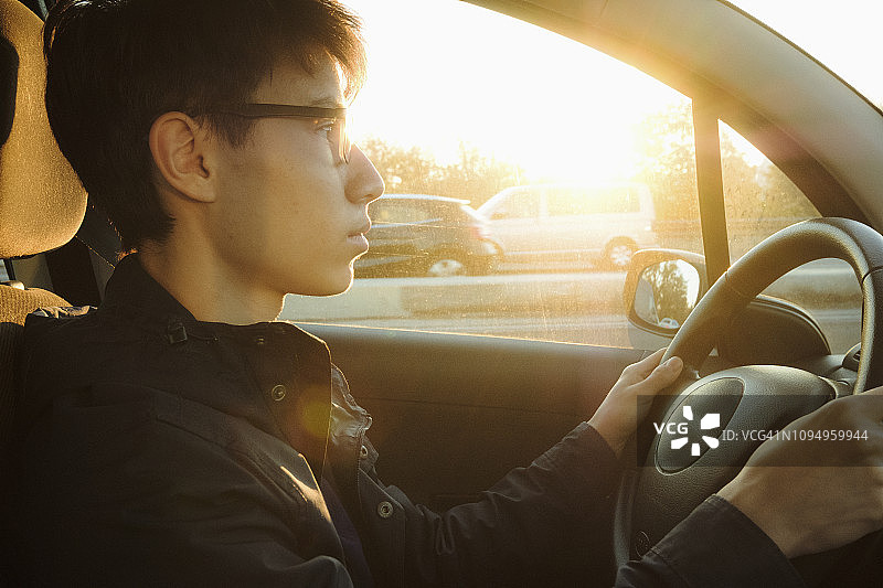 一个年轻人在阳光明媚的路上开车图片素材