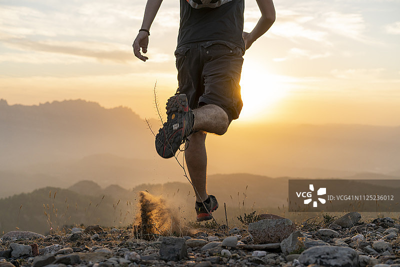 西班牙，巴塞罗那，圣洛伦克自然公园，日落时分，一名男子在山中奔跑图片素材
