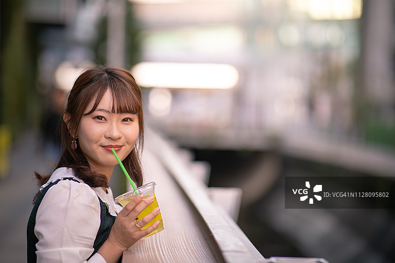 年轻女子在城市里喝着一杯果汁图片素材