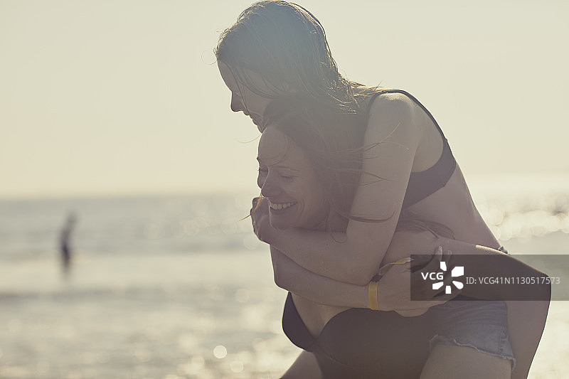 母亲和女儿微笑着，在海滩上拥抱拥抱图片素材