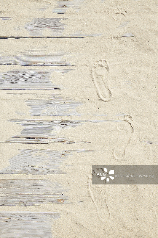 高角度观看沙滩上有脚印的木板路，通往海滩的小径图片素材