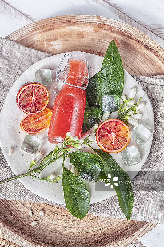 新鲜的血橙和果汁在翻盖瓶在乡村托盘木背景。图片素材