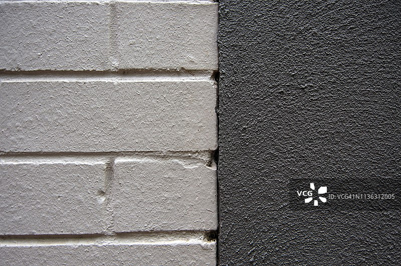 对比鲜明的建筑外墙:乳白色的砖墙和有纹理的灰色灰泥水泥图片素材