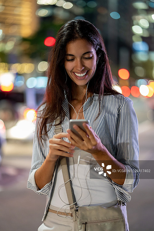 晚上在街上用手机聊天的快乐女人图片素材