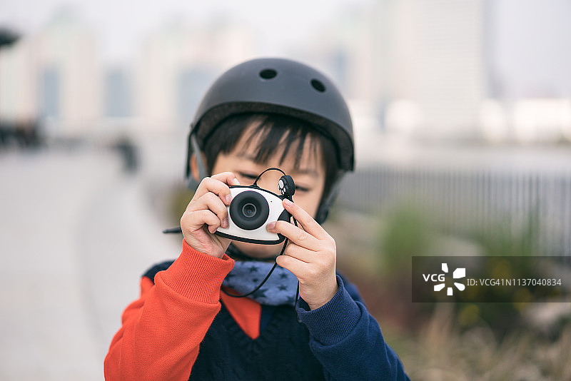 一个小男孩戴着运动头盔玩相机的特写图片素材
