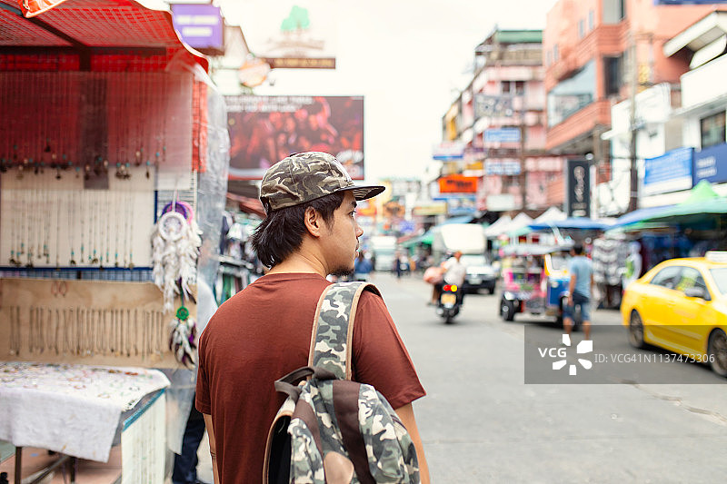 背面的年轻亚洲旅行青年走和看在考山路步行街在晚上在曼谷图片素材