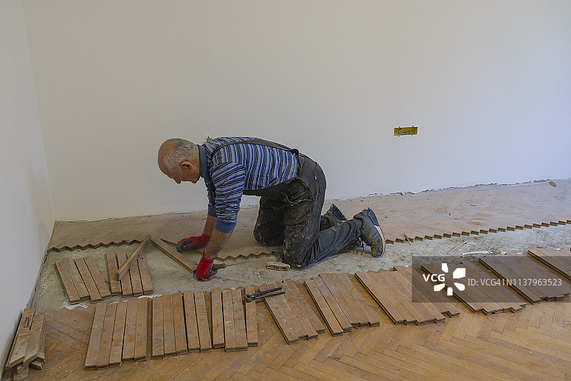 经验丰富的木匠正在通过更换地板来翻新房子图片素材