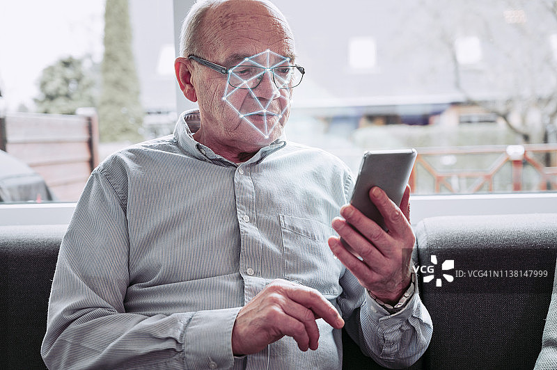 老人拿着手机，手机应用扫描他的脸图片素材