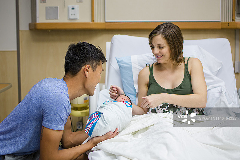 一位新妈妈和新爸爸骄傲地注视着他们刚出生的女儿图片素材