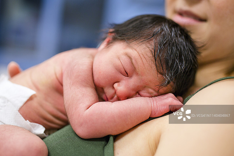 一位新妈妈轻轻地摇着她刚出生的女儿图片素材