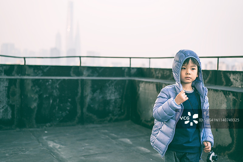 一个小男孩在中国上海高楼的屋顶上的肖像图片素材