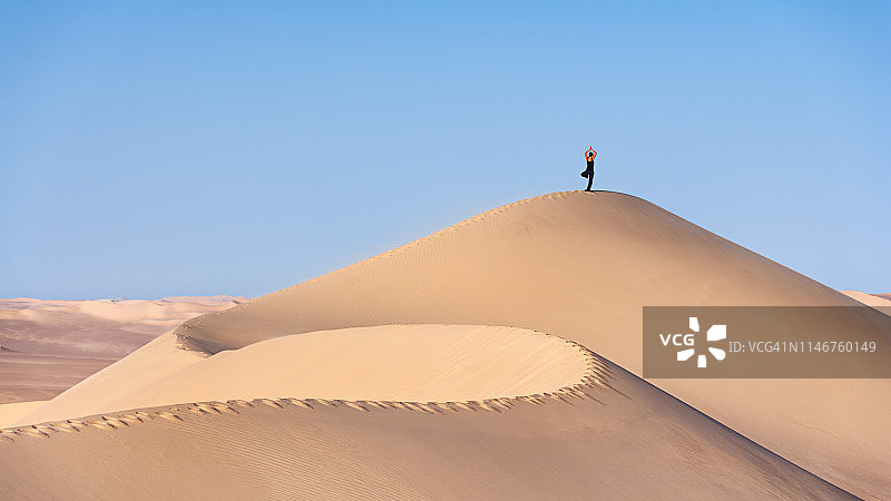 一名女游客在撒哈拉沙漠的沙丘上练习瑜伽图片素材