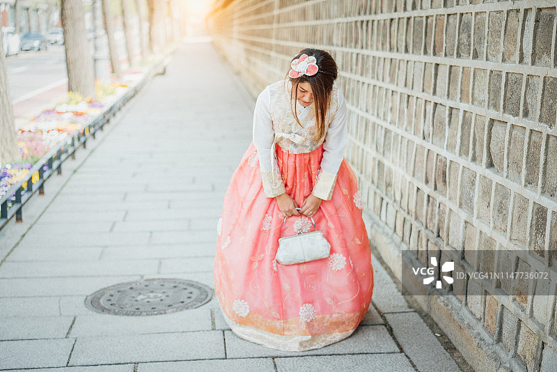 年轻的亚洲女游客穿着韩国的民族服装或韩服进入京福宫，韩国首尔。图片素材