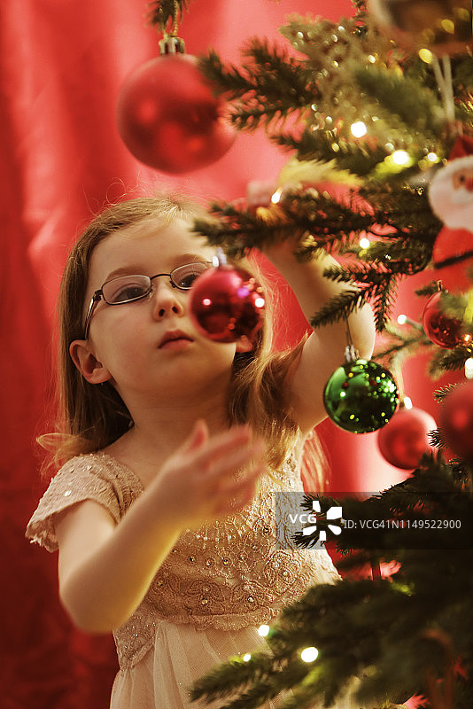 小女孩在圣诞树上挂装饰品图片素材