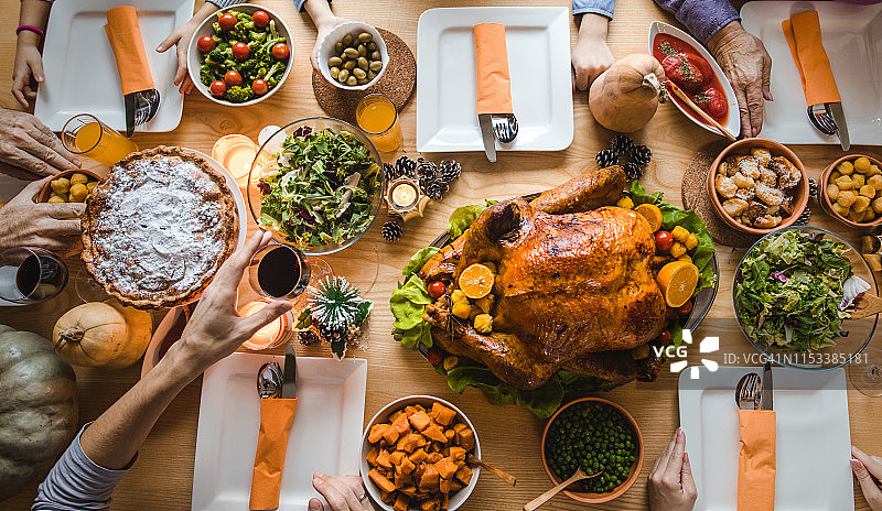 上图是一群面目全非的人在餐桌上吃感恩节晚餐。图片素材
