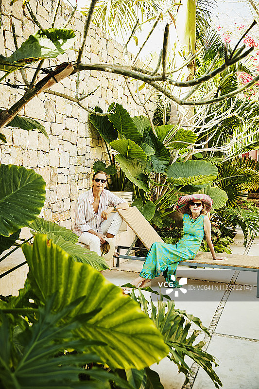 老年夫妇在热带度假胜地的花园放松的肖像图片素材