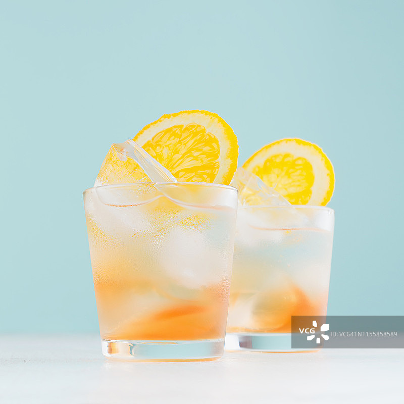 冷冻橙子酒精饮料与橙酒，切片水果，冰块在蓝色柔和的背景雾蒙蒙的小酒杯，正方形。图片素材