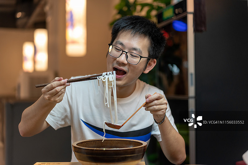 一名亚洲男子在餐馆里吃中国汤面图片素材