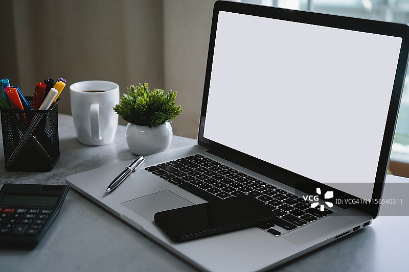 笔记本电脑与空白白屏幕和办公用品的文书桌上图片素材