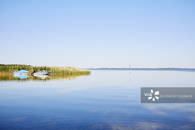 田园诗般的湖泊，芦苇草和小船映衬着蓝天图片素材