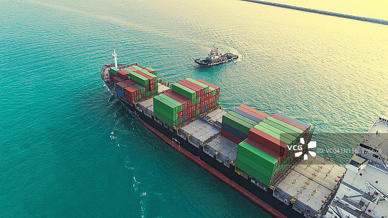 拖船、集装箱船到码头或集装箱仓库进行物流、进出口、航运或运输。图片素材