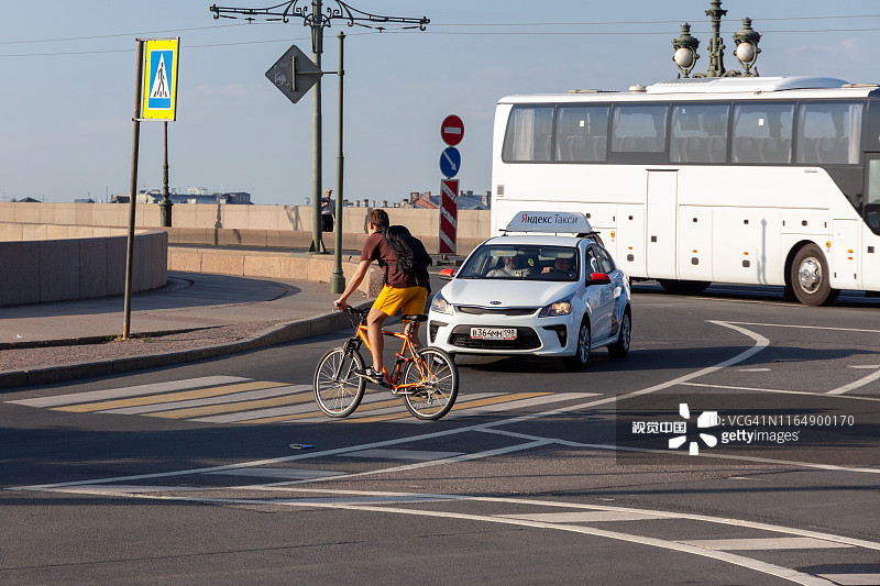 一个骑自行车的人在汽车前面的人行横道上过马路图片素材