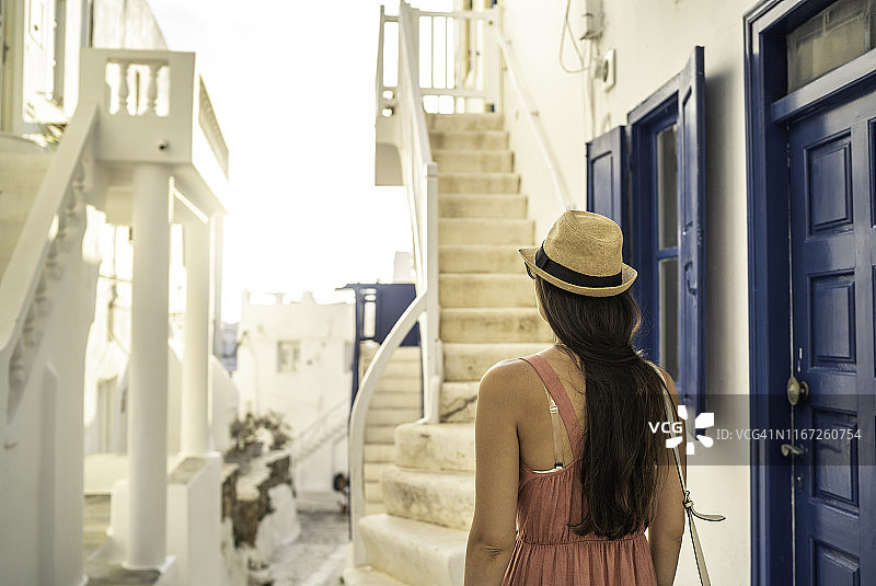 一个年轻女人的后视图行走和探索的街道的希腊城市图片素材