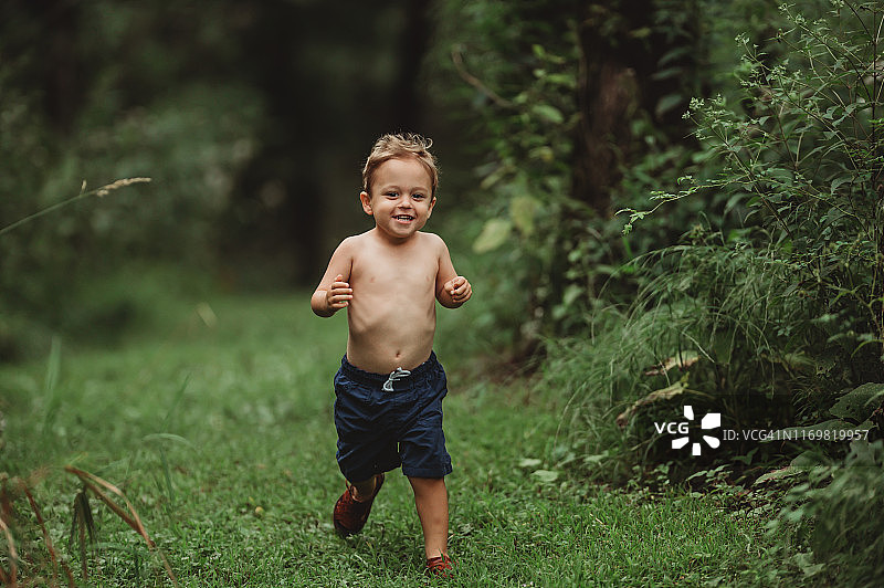 一个微笑的3.5岁小孩的肖像，谁是赤膊与凉鞋在森林图片素材