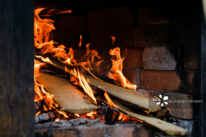 木板在火中燃烧，冒出橙色的火舌和烟雾。图片素材