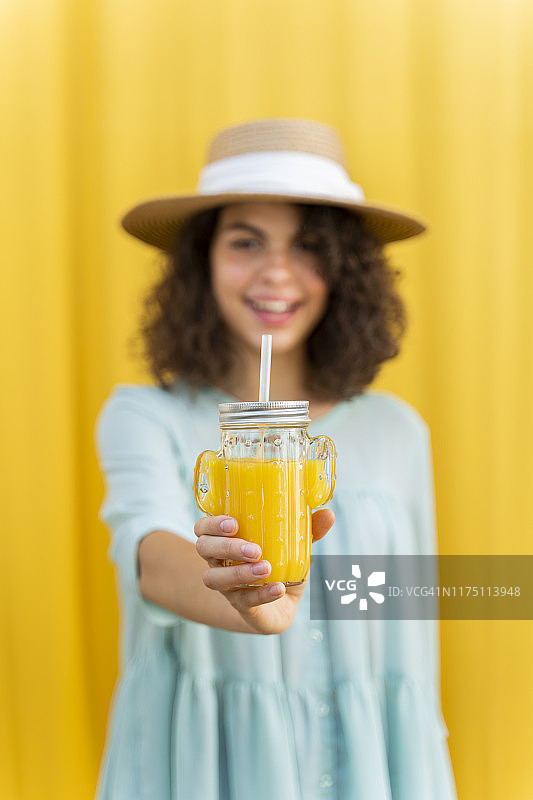 女子肖像戴草帽，喝果汁，黄色背景图片素材