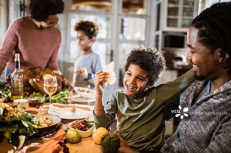 快乐的黑人男孩享受他的家人在餐厅感恩节。图片素材