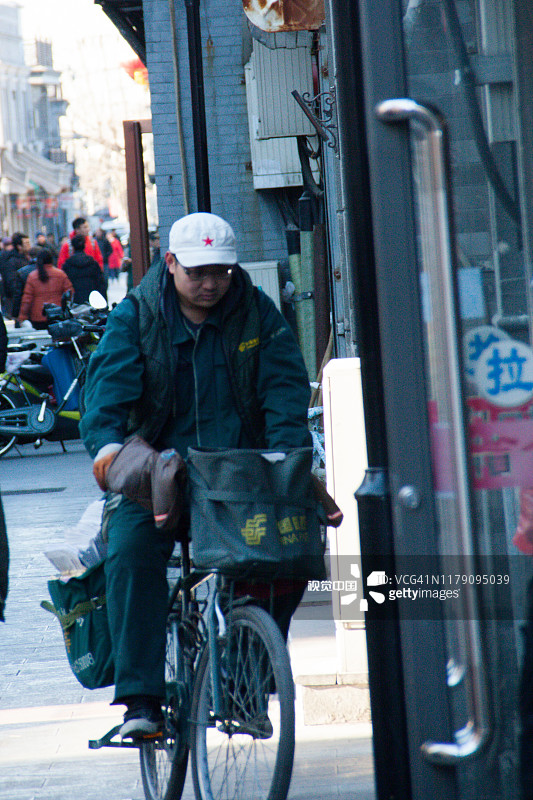 一名邮递员骑着自行车在北京前门购物区送信图片素材