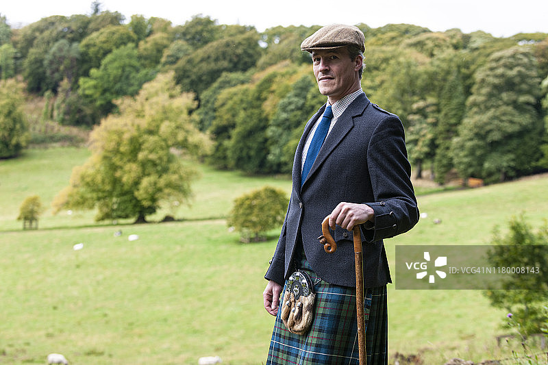 穿着苏格兰短裙和毛皮大衣的苏格兰男子，拄着手杖图片素材