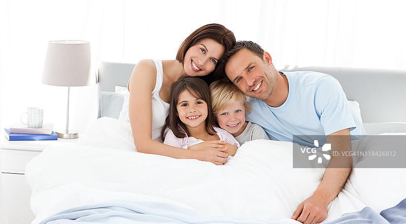 快乐的孩子和他们的父母在床上图片素材