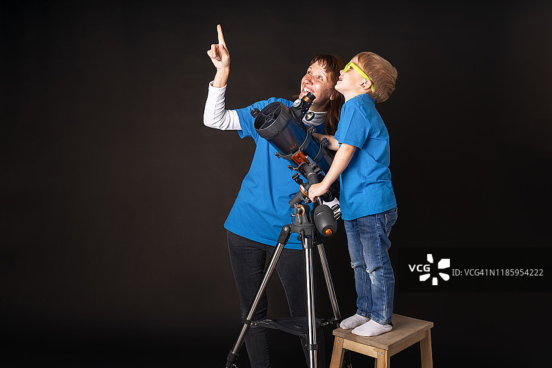 妈妈和儿子研究一个巨大的耐火望远镜并观察天空。图片素材